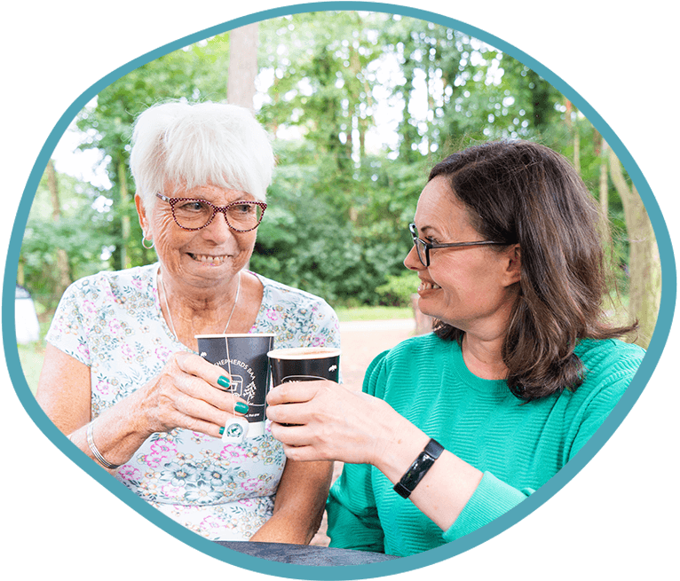 Female carer and female client outside drinking tea together