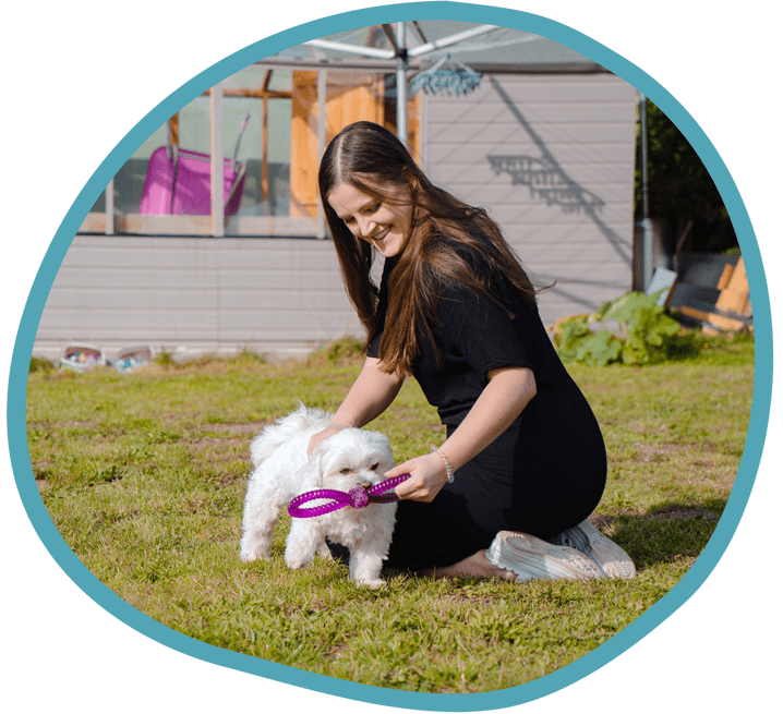 Female carer playing outside with little white dog