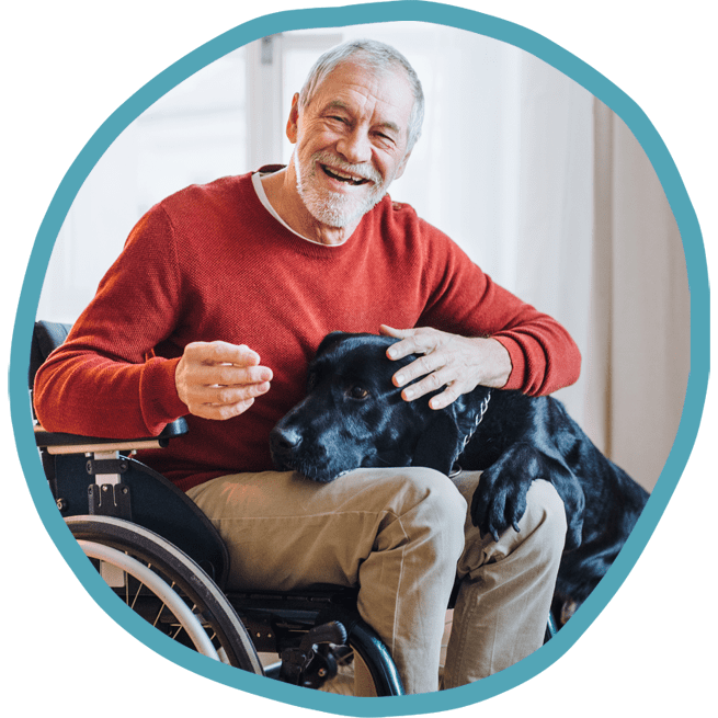 Male client in wheelchair smiling with his black labrador