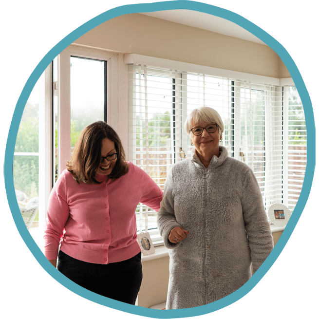 Female carer and female client walking in the conservatory