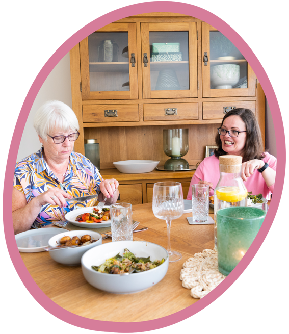 Female client with a female carer who is serving a healthy home cooked meal